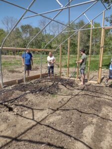 People holding irrigation tubing on a farm.