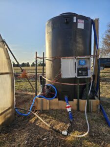 Installation photo of a 500 gallon water tank and small solar system at participating farm. 