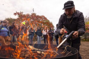 person with crank powered air suply stoking fire to in a biochar kiln