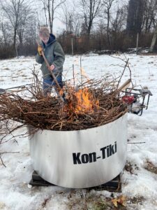 person tending to a kin-tiki biochar kiln at start
