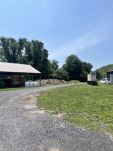 gravel road with open structure and compost pile in the background