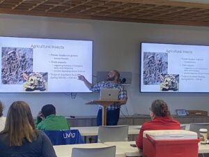 A man standing in front of a classroom pointing to photos on a projected slide