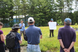 People standing to listen to field talk. Research plots in the background.