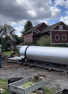 rolling a composter on round logs into a new position on the farm