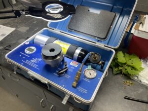 A machine on a workbench used to gather leaf water potential measurements. Measured and hole-punched grape and chestnut leaves sit beside the machine.