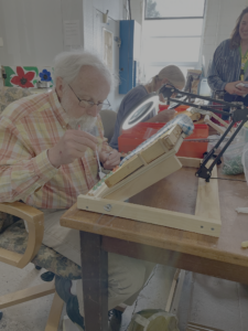 a participant in a honey bee care workshop is working at a table with a lamp.