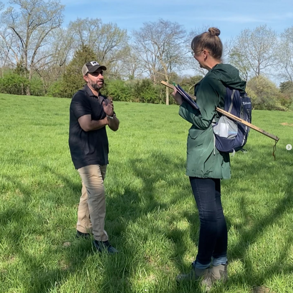 A man and woman speak in a pasture