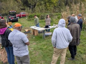 Farmers gather around a table and listen to an instructor talk about cover crops.