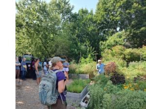 Man on the right points out farm to group of visitors on the left.