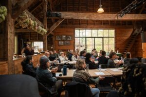 people siting at tables in an old barn