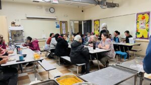 People sitting down for a meal at three cafeteria tables