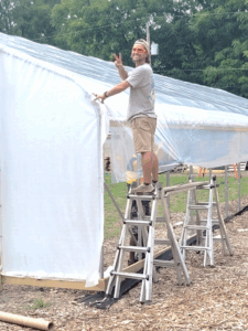 Incubator program participant helping construct high tunnel