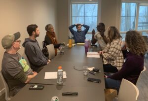 Farmers inside sitting at a conference table, brainstorming and discussing farming challenges.