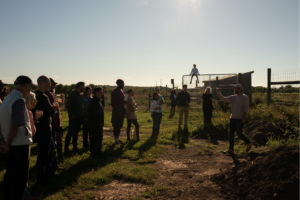 Farmer leading a tour in late afternoon sun.