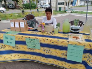 A YSC member selling teas and other drinks at a farmers market booth.