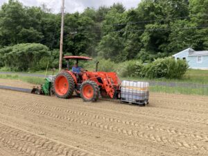 Figure 5: John Janiszyn applies urine fertilizer to the ground as he simultaneously lays down a row of plastic mulch for growing pumpkins at his field in Westminster, VT.
