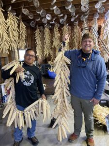 Cherokee farmers hold braids of corn they learned to weave.