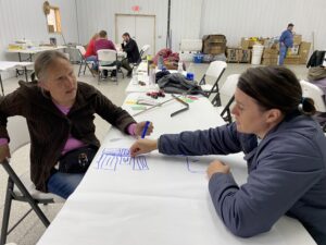 Two women draw an irrigation system plan