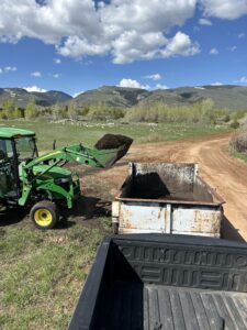 Tractor moving compost into dump trailer