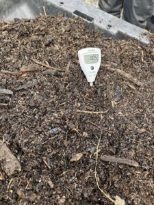 A salinity meter placed in a tote of brown organic matter. 