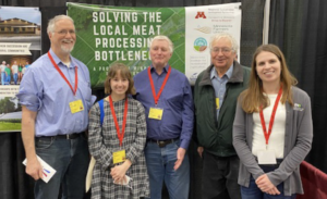 The MFU Bottleneck team standing in front of their MAMP booth at the MAMP annual convention. Five people are shown, from left: Don Arnosti, Maya Benedict, Ted Suss, Paul Sobocinski, and Courtney VanderMey.