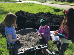 Children ammending the soil with cal and compost before planting. Photo by Jon Zirkle